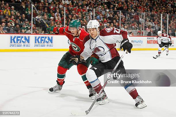 Darroll Powe of the Minnesota Wild and Steve Downie of the Colorado Avalanche skate to the puck during the game on January 19, 2013 at the Xcel...