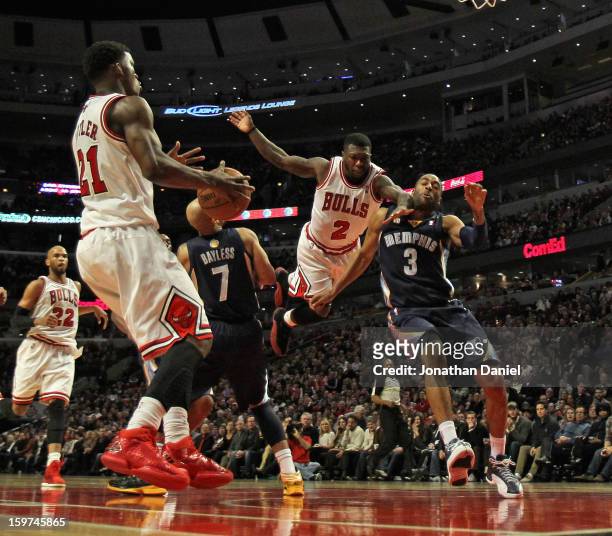 Nate Robinson of the Chicago Bulls leaps to pass to Jimmy Butler between Jerryd Bayless and Wayne Ellington of the Memphis Grizzles at the United...