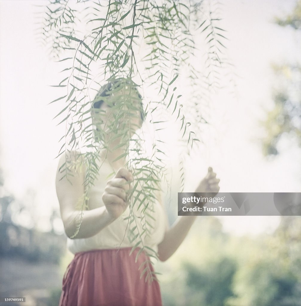 Portrait of a woman hiding behind a branch