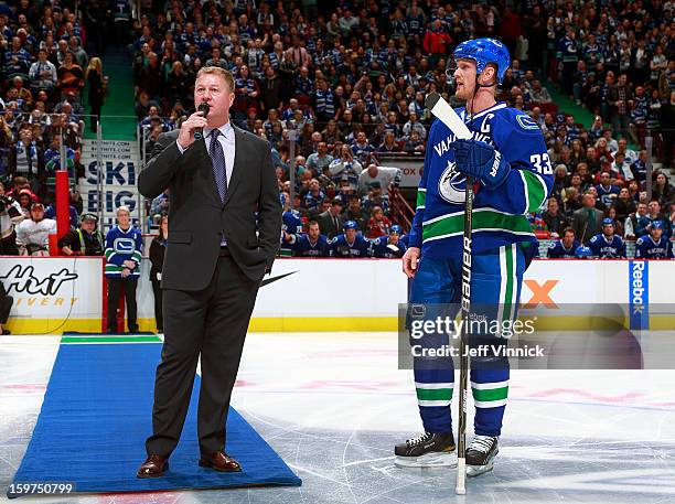 Vancouver Canucks captain Henrik Sedin looks on as Canucks General Manager Mike Gillis thanks the fans before their season-opening NHL game against...