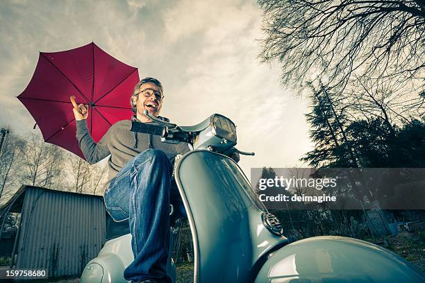 vue de bas-angle élevé d'homme sur un scooter rouge parapluie - moto humour photos et images de collection