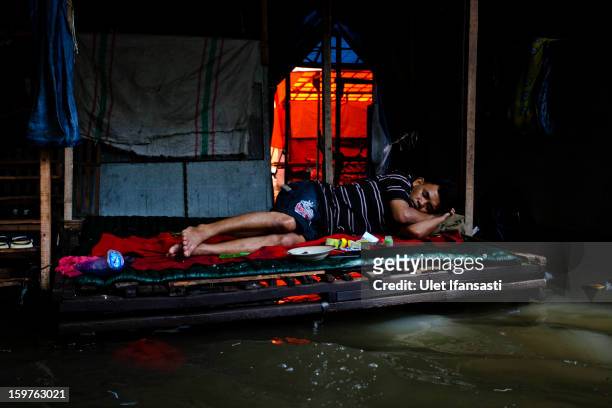 Man sleeps as flood waters lap beneath his make-shift bed, as major floods hit North Jakarta on January 20, 2013 in Jakarta, Indonesia. The death...