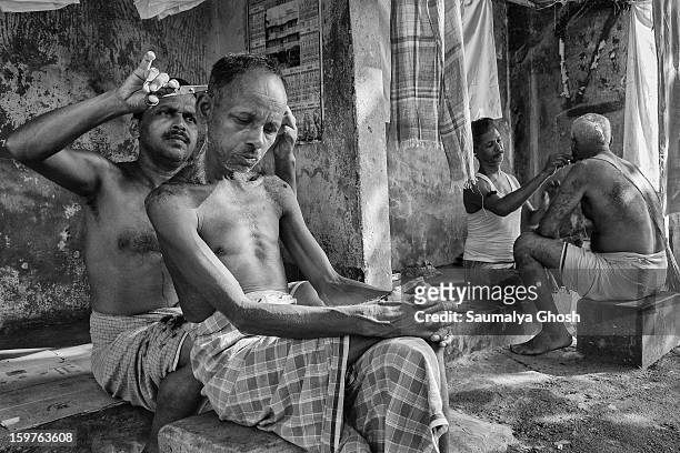 Typical roadside salon in Kolkata. One man is getting a haircut and another person is getting a shave.