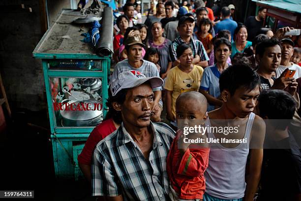 People queue for food aid as major floods hit North Jakarta on January 20, 2013 in Jakarta, Indonesia. The death toll has risen to at least 21 since...