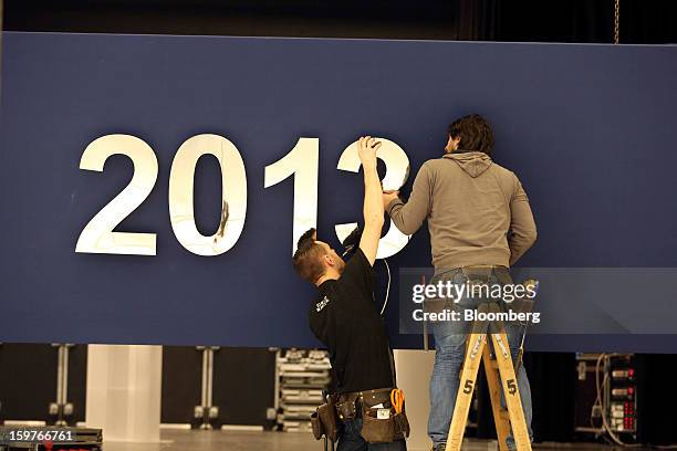 Workers prepare a section of the World Economic Forum 2013 sign inside the Congress Centre ahead of the WEF meeting in Davos, Switzerland, on Sunday,...