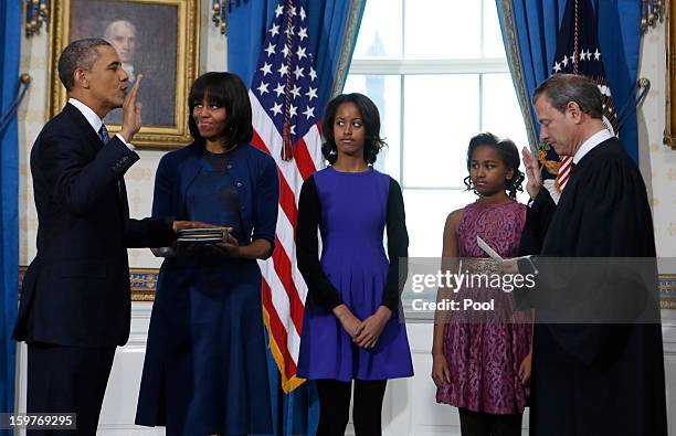 President Barack Obama takes the oath of office from U.S. Supreme Court Chief Justice John Roberts as first lady Michelle Obama holds the bible and...