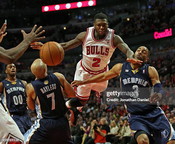 Nate Robinson of the Chicago Bulls leaps to pass between Jerryd Bayless and Wayne Ellington of the Memphis Grizzles at the United Center on January...