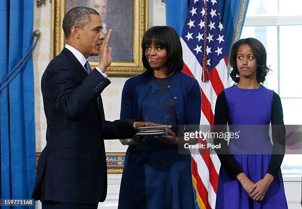 President Barack Obama takes the oath of office as first lady Michelle Obama holds the bible as daughter Malia looks on in the Blue Room of the White...