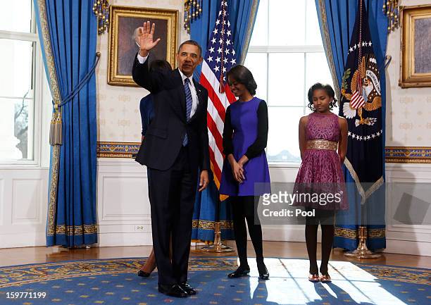 President Barack Obama waves as daughters Malia and Sasha look on in the Blue Room of the White House January 20, 2013 in Washington, DC. Obama and...