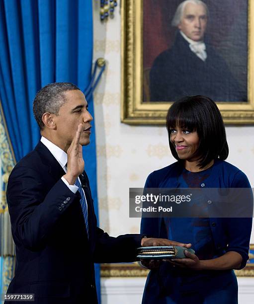 President Barack Obama takes the oath of office as first lady Michelle Obama holds the bible in the Blue Room of the White House January 20, 2013 in...