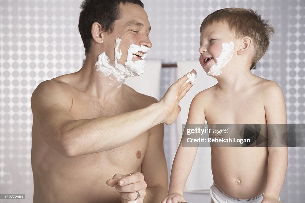 Small boy having fun shaving with dad.