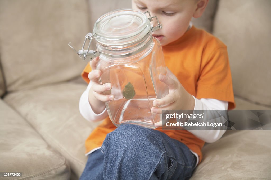 Small boy with frog in jar.