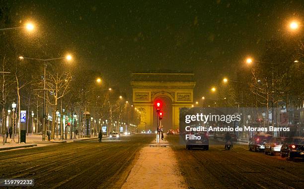 People make their way along the Champs-Elysees as snow falls on January 20, 2013 in Paris, France. Heavy snowfall fell throughout Europe and the UK...