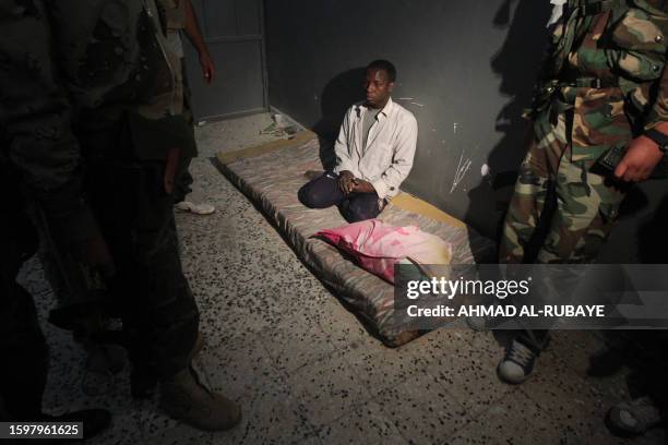 Libyan National Transitional Council fighters detain a suspected mercenary fighter loyal Moamer Kadhafi during battles in the streets of Sirte on...