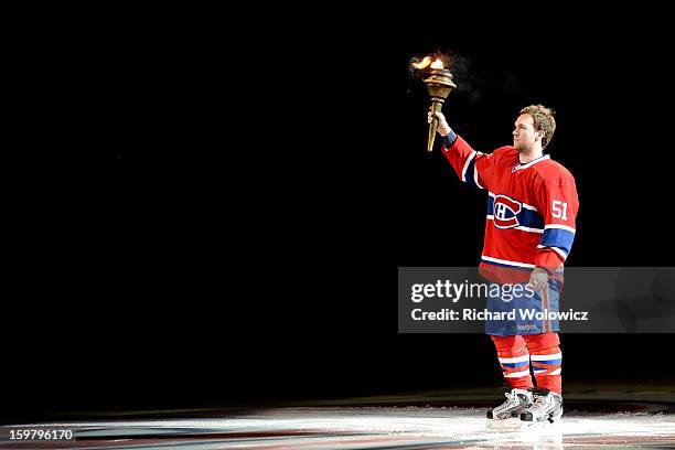 David Desharnais of the Montreal Canadiens raises a torch during pre-game ceremonies prior to facing the Toronto Maple Leafs in their NHL game at the...