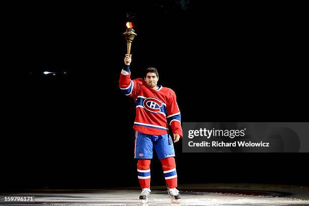 Francis Bouillon of the Montreal Canadiens of the Montreal Canadiens raises a torch during pre-game ceremonies prior to facing the Toronto Maple...