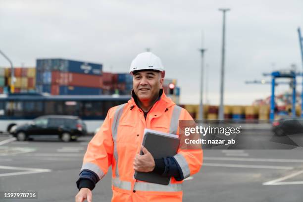 ingeniero en ropa de protección en el lugar de trabajo con planos digitales. - puerto fotografías e imágenes de stock