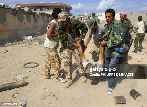 Libyan National Transitional Council fighters carry a comrade who was wounded during a street battle in Sirte on October 18, 2011. Fierce street...