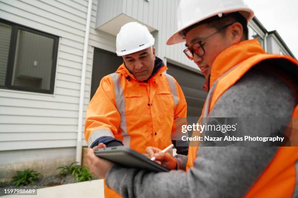 blue collar workers examine houses after development. - real estate developer stock pictures, royalty-free photos & images