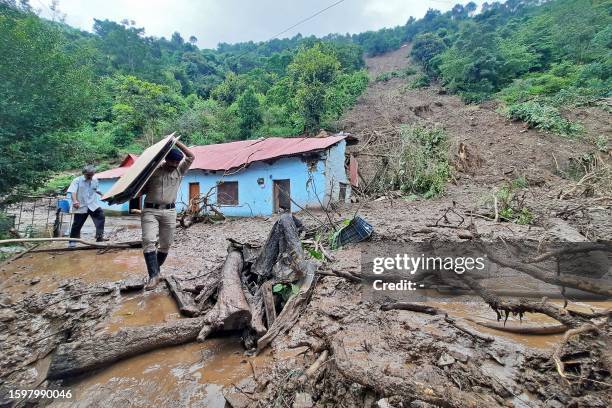 Security personnel carries the belongings of a villager from the site of a landslide after heavy rains at Jadon village in Solan district of India's...