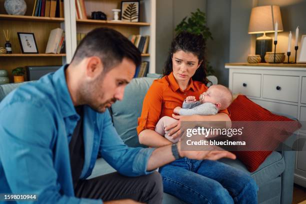 mid adult couple arguing on sofa at home. - relatieproblemen stockfoto's en -beelden