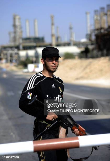 Libyan rebel stands guard at the entrance to the Zawiya oil refinery, some 40 kms west of Tripoli, on August 19, 2011. Libyan rebels pushing to cut...