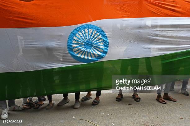 Supporters of Bharatiya Janata Party carry a giant Indian national flag on the eve of country's Independence Day in Hyderabad on August 14, 2023.