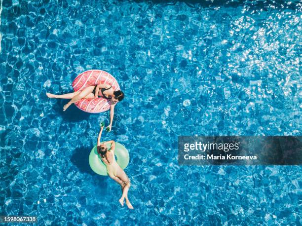 friends on an inflatable ring floating in the pool. drone point of view. - cocktail ring stock-fotos und bilder