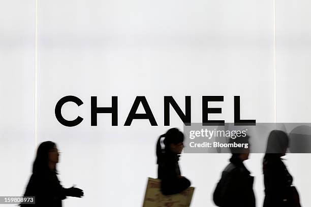 Pedestrians walk past signage for Chanel SA outside the company's store in the Omotesando district of Tokyo, Japan, on Saturday, Jan. 19, 2013....