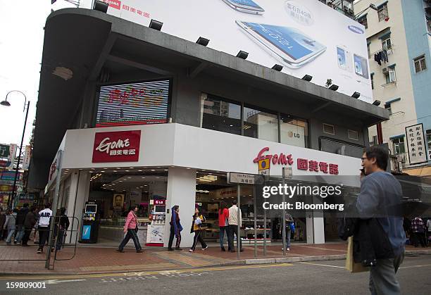 Man crosses the road in front of a Gome-branded store in the district of Tsuen Wan in Hong Kong, China, on Monday, Jan. 21, 2012. Gome Electrical...