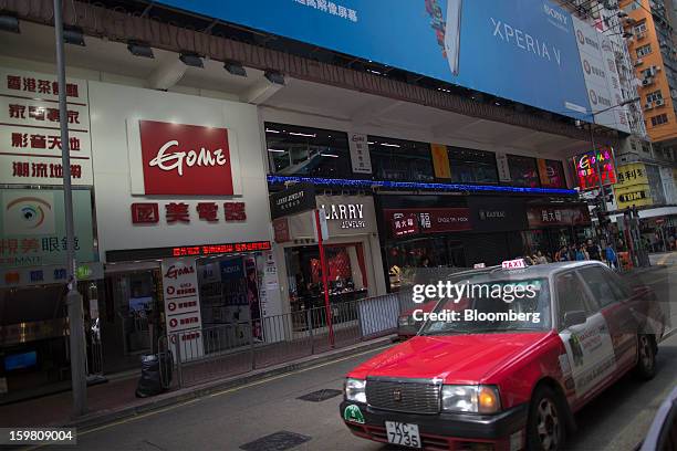 Taxis drive past the entrance of a Gome-branded store in the shopping district of Causeway Bay in Hong Kong, China, on Monday, Jan. 21, 2012. Gome...