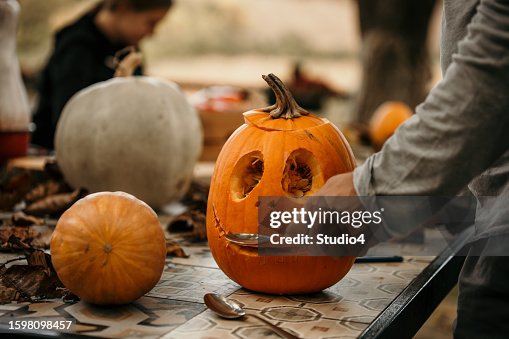 Famille célébrant Halloween à la maison et préparant des citrouilles. Fille créative faisant une décoration d’Halloween. Famille célébrant Halloween à la maison et préparant des citrouilles. Fille créative faisant une décoration d’Halloween.