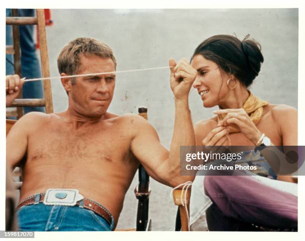 Shirtless Steve McQueen sitting next to Ali MacGraw on the set of the film 'The Getaway', 1972.