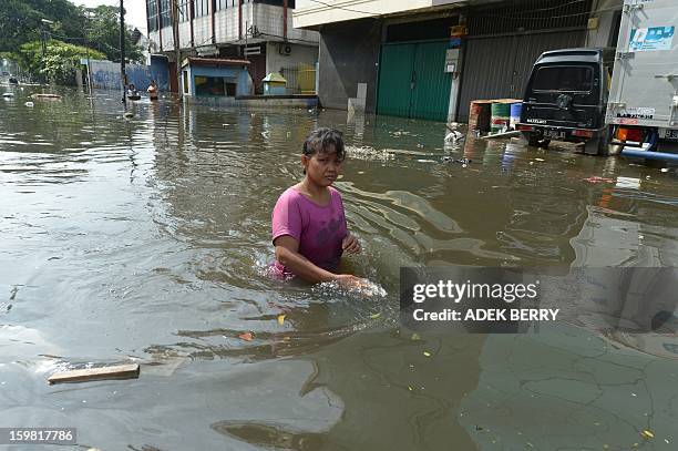 Indonesian men row a rubber boat past trucks inundated by floodwaters in Penjaringan subdistrict in Jakarta on January 21, 2013. Companies and...