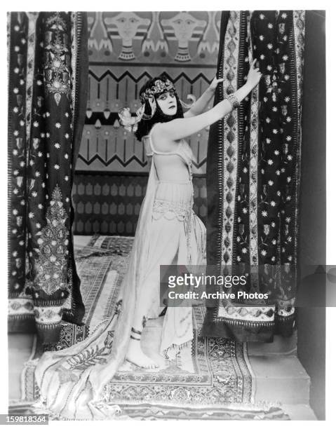 Theda Bara holds onto a curtain in a scene from the film 'Cleopatra', 1917.