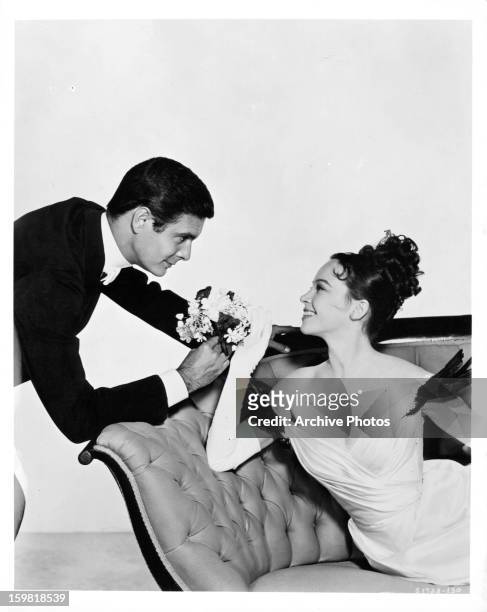 Louis Jourdan offering flowers to Leslie Caron in publicity portrait for the film 'Gigi', 1958.