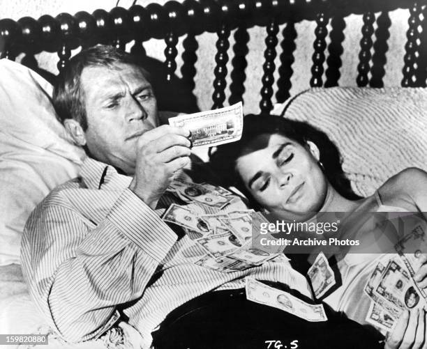 Steve McQueen and Ali MacGraw counting their money in bed in a scene from the film 'The Getaway', 1972.