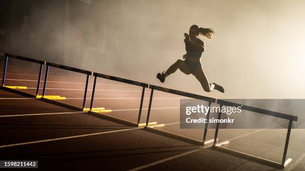 athlet springt über hürde - damen leichtathletikdisziplin stock-fotos und bilder