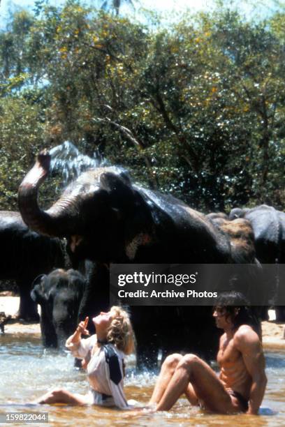 Bo Derek sitting in an elephant's watering hole with them in a scene from the film 'Tarzan The Ape Man', 1981.