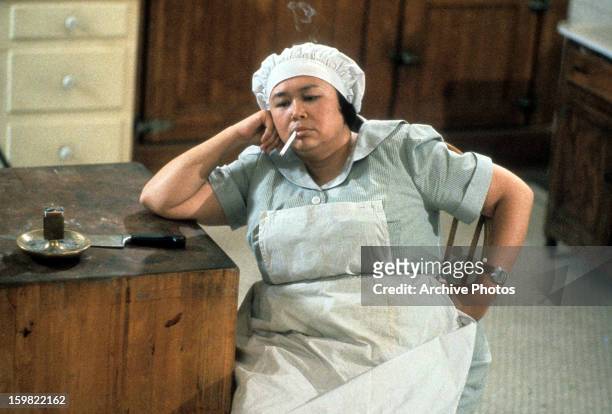 Kellye Nakahara dressed in a maids uniform while smoking a cigarette in a scene from the film 'Clue', 1985.