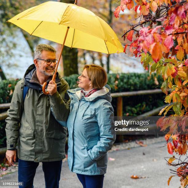 mature couple enjoying a rainy day - man in rain jacket stock pictures, royalty-free photos & images