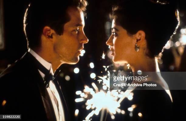 Sweeney and Moira Kelly looking passionate into one an others eyes as fireworks go off in the background in a scene from the film 'The Cutting Edge',...