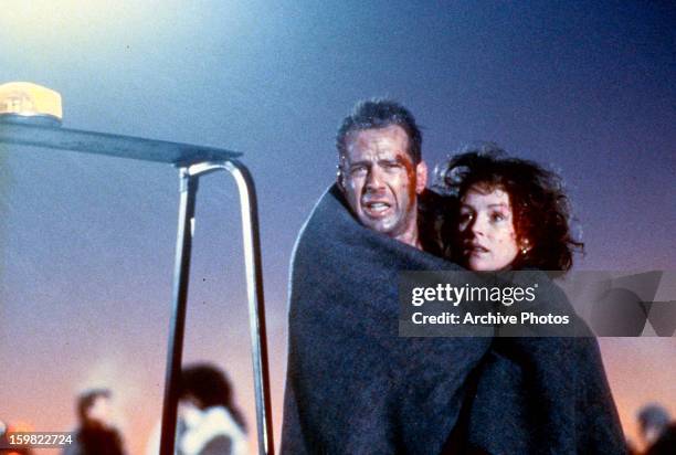 Bloodied Bruce Willis and Bonnie Bedelia wrapped in blanket in a scene from the film 'Die Hard 2', 1990.
