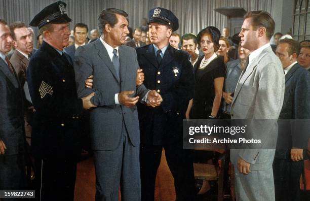 Cary Grant is restrained by two officers in a scene from the film 'North By Northwest', 1959.