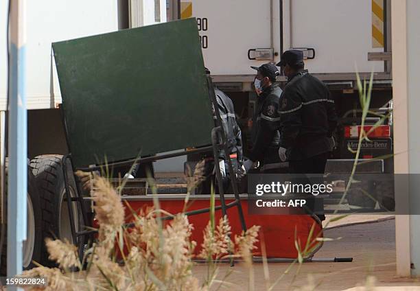 Algerian security personnel use a board and stretcher to conceal from the media as they remove body bags of victims, that were killed during the...