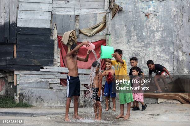 Children splash water over a boy amidst soaring temperatures at the Shati camp for Palestinian refugees in Gaza City on August 14, 2023.