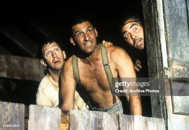 Tim Blake Nelson, John Turturro, and George Clooney look outside of a barn in a scene from the film 'O Brother, Where Art Thou?', 2000.