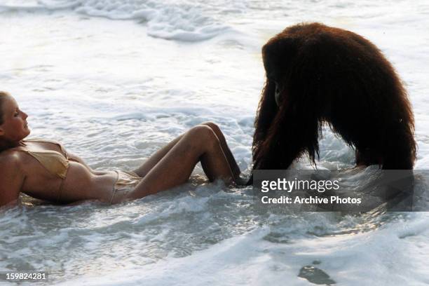 Bo Derek in ocean with ape at her feet in a scene from the film 'Tarzan, The Ape Man', 1981.