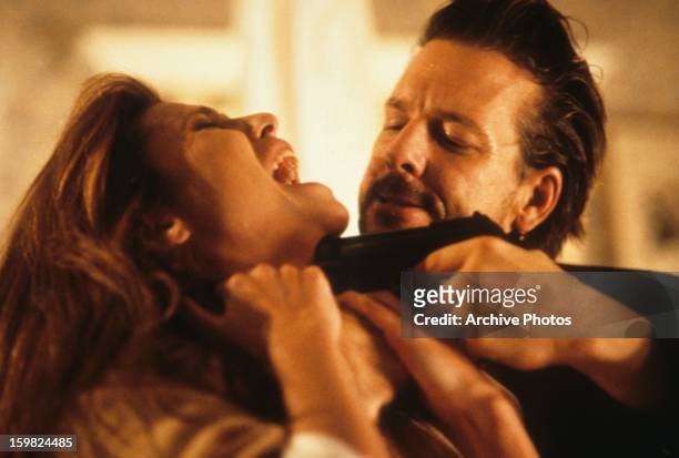 Lindsay Crouse has a gun held against her throat by Mickey Rourke in a scene from the film 'Desperate Hours', 1990.