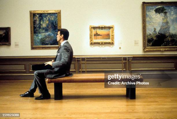 Pierce Brosnan sitting on a bench in an art gallery in a scene from the film 'The Thomas Crown Affair', 1999.